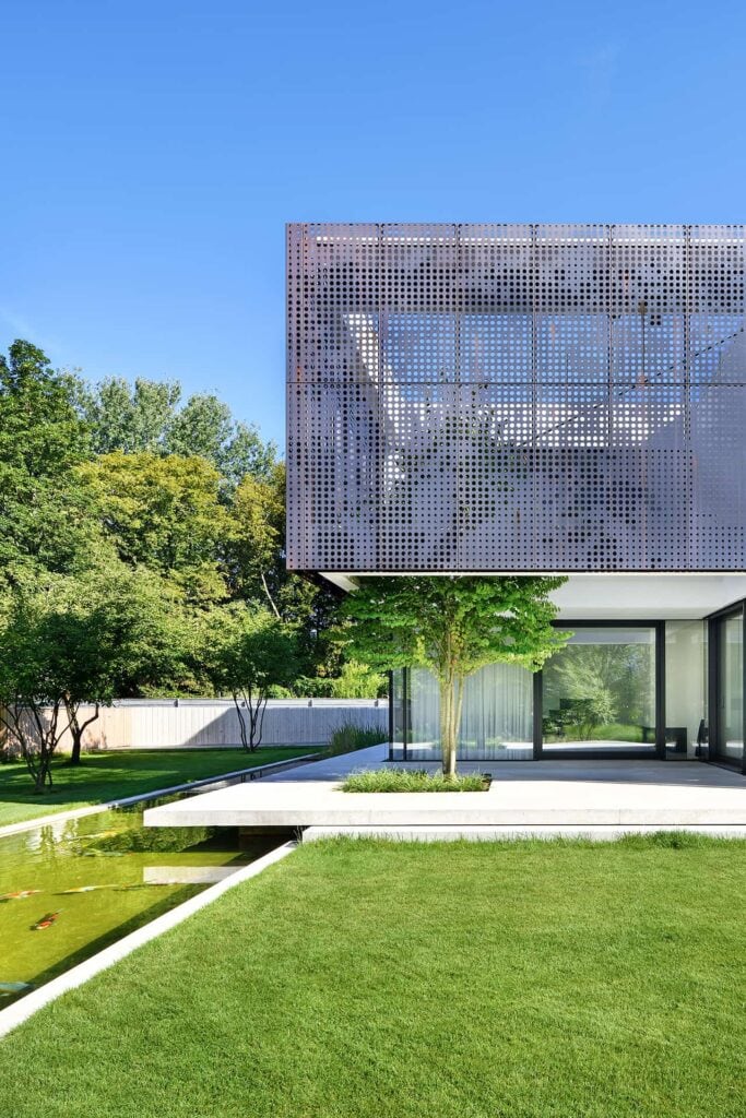 Eine moderne Villa in Niederbayern, die Fassade besteht aus gelochten Kupferkassetten, im Vordergrund ein toller Garten inklusive Koiteich.