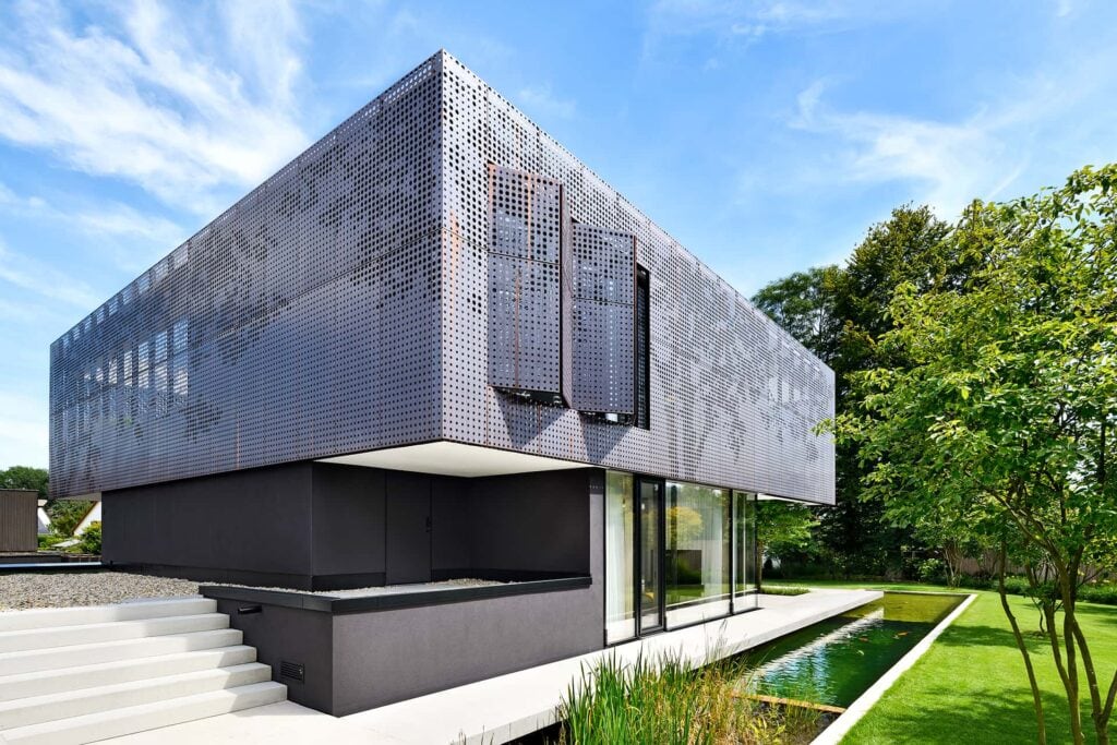 Eine moderne Villa in Niederbayern, die Fassade besteht aus gelochten Kupferkassetten, im Vordergrund ein toller Garten inklusive Pool.